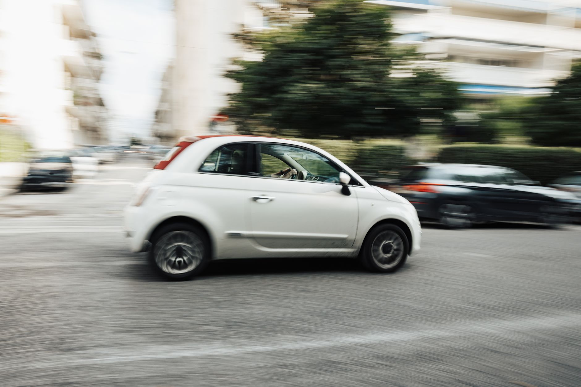 Biały Peugeot jedzie szybko ulicą miasta, rozmyte tło podkreśla ruch