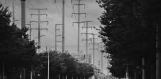 Czarno-biała ulica miasta z liniami energetycznymi i samotnym przechodniem