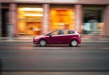 Peugeot 207 1.4 i 1.6 opinie spalanie typowe usterki czy warto dziś kupić Czerwony Peugeot 207 jedzie szybko po miejskiej ulicy