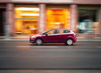 Peugeot 207 1.4 i 1.6 opinie spalanie typowe usterki czy warto dziś kupić Czerwony Peugeot 207 jedzie szybko po miejskiej ulicy