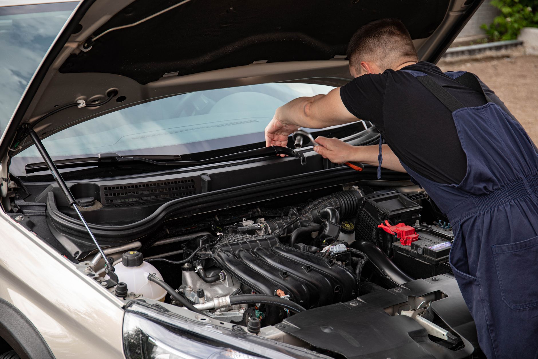 Mechanik naprawia silnik samochodu na zewnątrz w jasny dzień