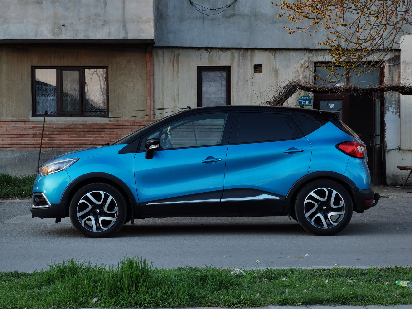 Niebieskie Renault Captur drugiej generacji zaparkowane przy kamienicy