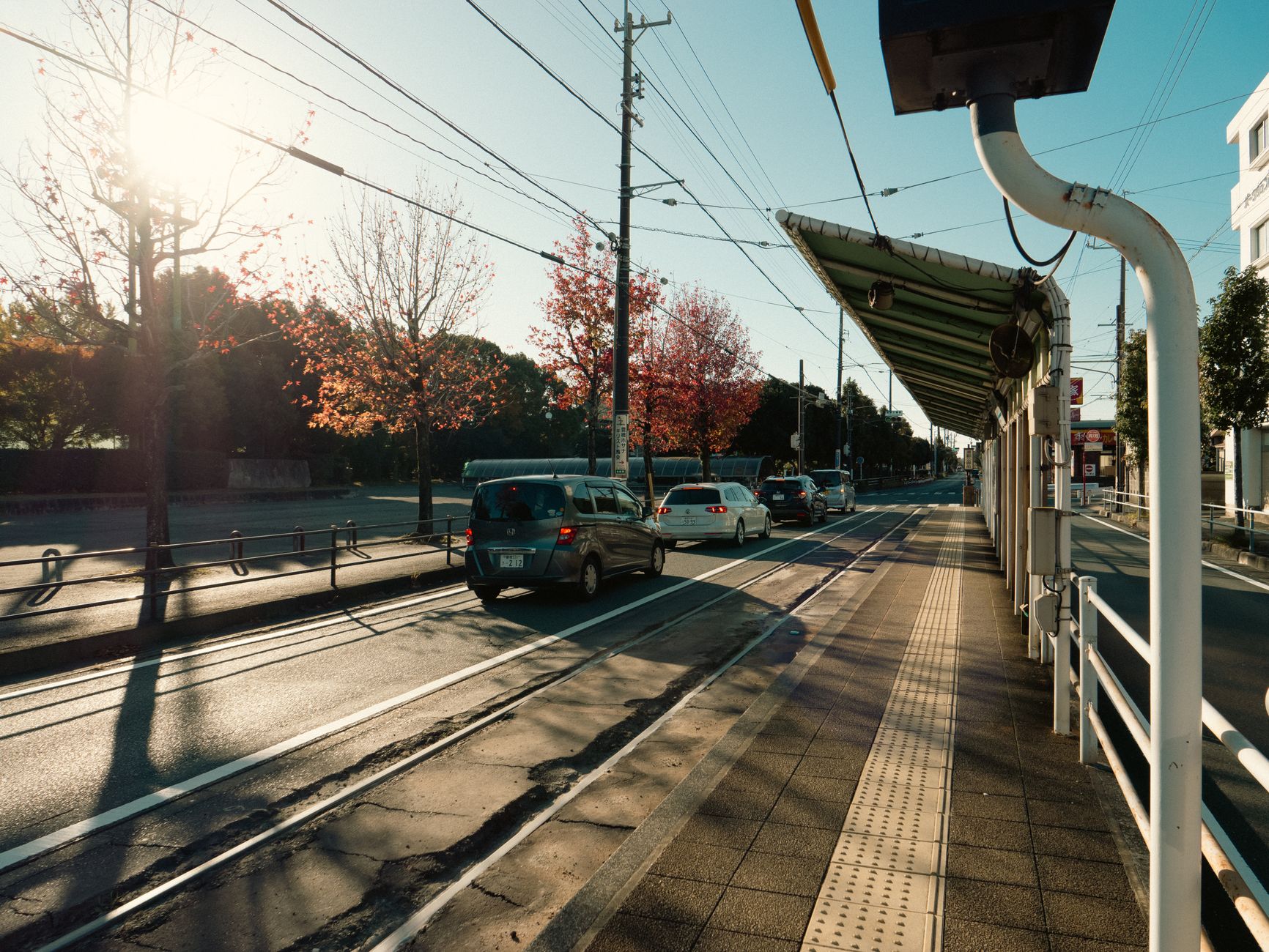 Tramwaj i samochody na słonecznej ulicy w japońskim mieście