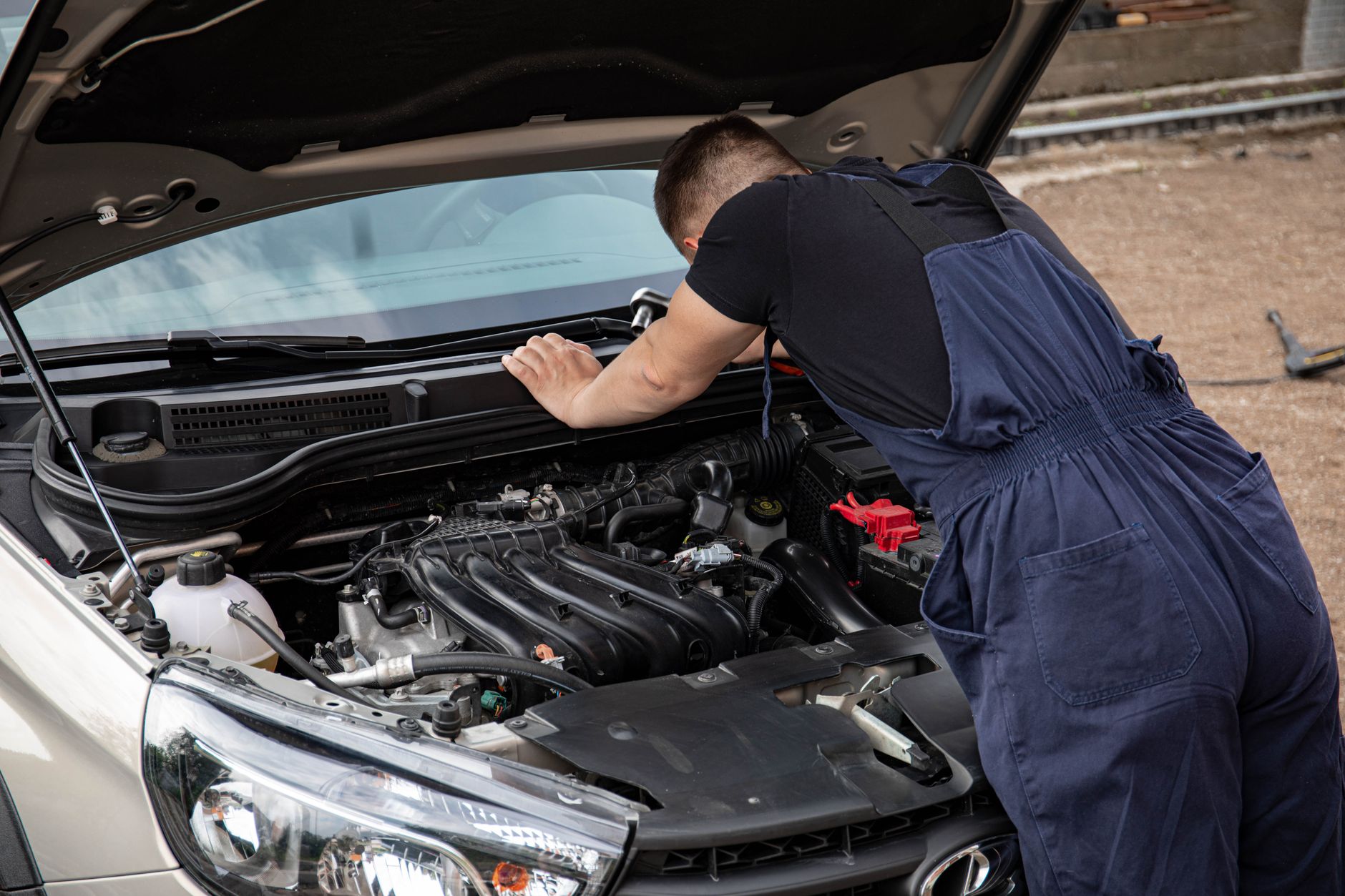 Mechanik sprawdza silnik benzynowy Peugeota na zewnątrz