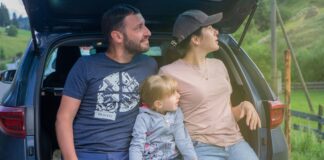 Rodzina siedząca w bagażniku auta podczas wypoczynku na wsi