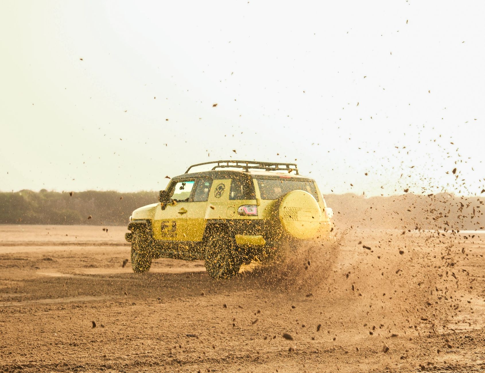 Żółty SUV 4x4 wzbijający kurz podczas jazdy w terenie