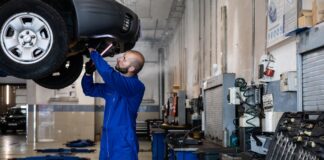 Najczęstsze usterki Toyoty Auris Hybrid – co psuje się w używanych egzemplarzach? Mechanik sprawdza podniesiony samochód w warsztacie samochodowym