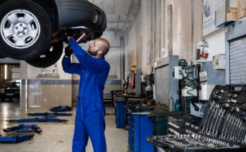 Najczęstsze usterki Toyoty Auris Hybrid – co psuje się w używanych egzemplarzach? Mechanik sprawdza podniesiony samochód w warsztacie samochodowym